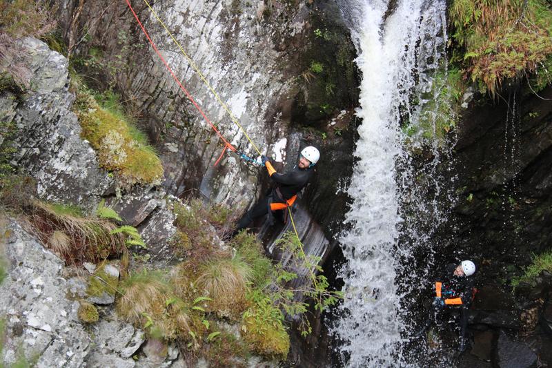 Canyoning abseil through waterfall